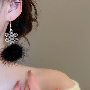 Detail of snowflake acrylic flower earrings with plush black pompom for winter