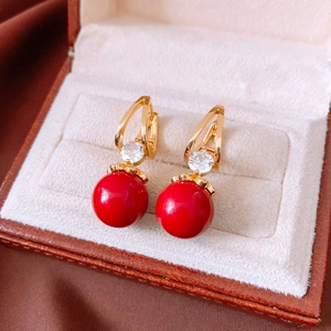Close-up of red resin pearl earrings with gold hooks and zircon in a premium jewelry box