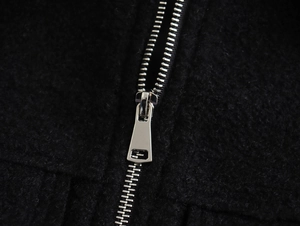 Détail macro de la fermeture éclair argentée sur une veste courte noire en laine