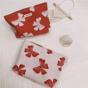 Detail of canvas makeup bags with red and white bow prints and simple wish fabric label