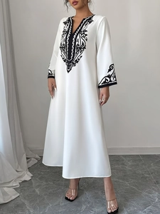 Dettaglio del ricamo sullo scollo a V e nappe su questo elegante abito lungo kaftan bianco