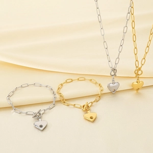 Golden and silver heart pendant necklaces and bracelets on beige silk fabric background