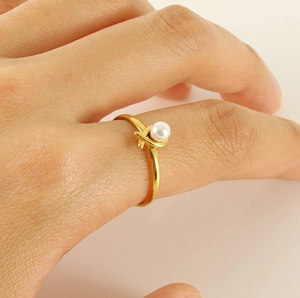 Detailed macro view of a gold-plated stainless steel ring with a round white pearl