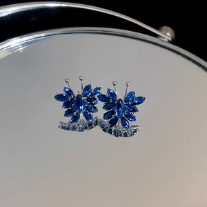Macro shot of silver butterfly earrings with marquise-cut deep blue zircon stones