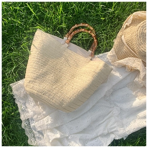 Detail of straw tote bag with bamboo handles on white lace cloth in a summer garden setting