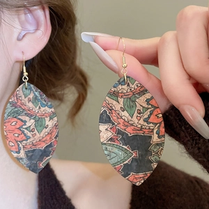Detailed macro view of vintage ethnic leaf-shaped earrings with colorful printed leather