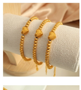 Vue détaillée de trois bracelets à billes plaqués or 18 carats avec pendentifs en cœur