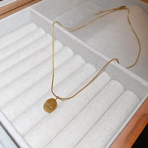 Détail d'un pendentif ovale doré avec gravure You are beautiful dans un écrin en bois