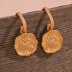 Detail shot of vintage 18K gold plated stainless steel sunburst coin earrings on wood