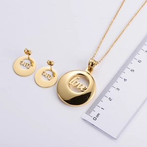 Golden titanium steel jewelry set with LOVE hollow pendant and earrings on white background