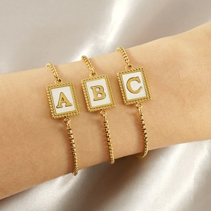 Adjustable gold stainless steel shell letter bracelet on elegant silk background