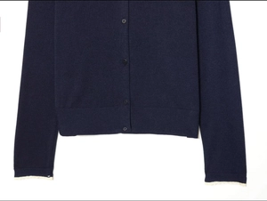 Detailed close-up of navy knit cardigan featuring round buttons and white lace cuffs