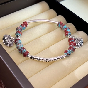 Detailed shot of ceramic beaded bracelet with silver longevity lock pendants in jewelry box
