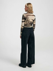 Vista posteriore di una donna che indossa un top mimetico aderente e jeans a gamba larga