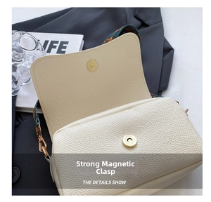 Detail of off-white pebble grain leather bag featuring a strong magnetic gold buckle closure