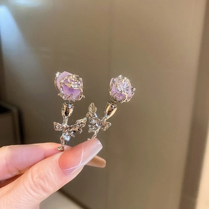 Macro shot of detailed purple resin rose earrings with silver metal flower stem and leaf