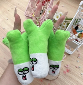 Close-up of green scallion plush charms with cute embroidered cartoon faces and gold clips