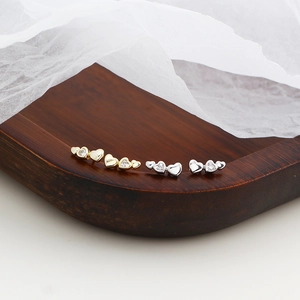 Detailed view of heart-shaped silver stud earrings in gold and silver finish with stones