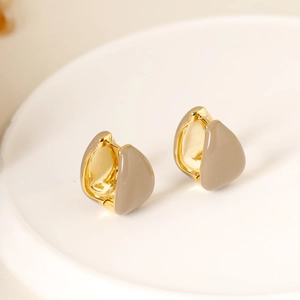 Detailed view of gold-plated teardrop enamel earrings on a white ceramic tray