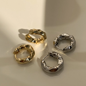 Detail von gold- und silberfarbenen Creolen mit strukturierter Lava-Metall-Optik