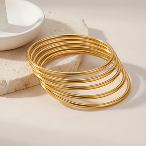 Detail showing high-polished 3mm gold stackable stainless steel bangles on stone