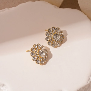 Close-up of elegant gold flower stud earrings with sparkling crystals on stone base