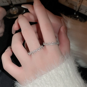 Detail of silver crisscross pearl rings with pavé cubic zirconia on a warm sweater background