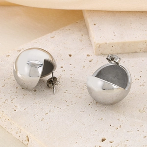 Minimalist silver spherical stud earrings displayed on premium beige stone background
