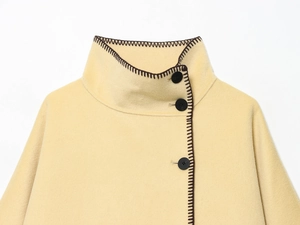 Close-up of beige wool coat featuring high collar, black buttons and dark hand-stitched edges