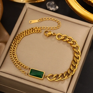 Detail of golden link bracelet with emerald cut green gemstone on jewelry box