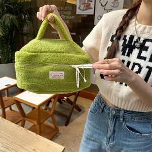 Detail of plush lime green cosmetics bag with woven label and white ribbon puller