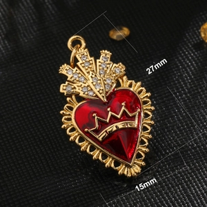 Macro view of a 27mm gold heart pendant with red enamel, crown top and crystal inlay