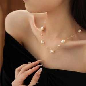 Detail of gold-plated necklace with irregular and small round pearls on a model neck