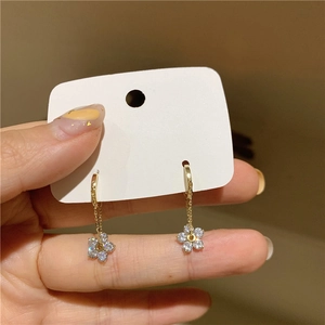 Close-up of gold flower earrings with sparkling crystals held in hand showing fine detail