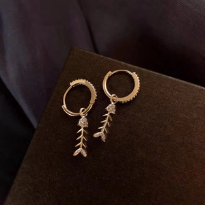 Golden mermaid tail hoop earrings with crystals on a textured jewelry box
