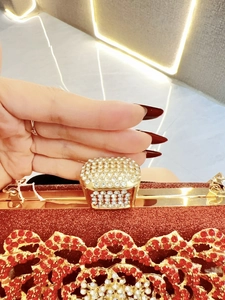 Detail of red glitter evening bag with gold metal frame and sparkling crystal clasp