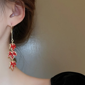 Gros plan de boucles d'oreilles vintage en feuilles d'érable dorées et strass rouges