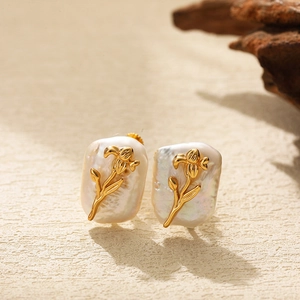 Macro detail of baroque pearl earrings with golden flower accents in Chinese style