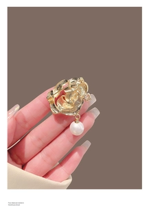 Détail de la broche fleur avec perle montrant le dos doré et le fermoir à épingle