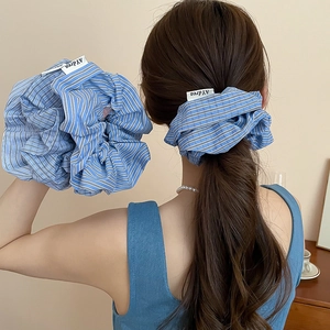 Detailed close-up of a blue and white striped fabric scrunchie with brand logo tag