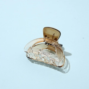 Detail of transparent and gold semi-round hair claw clip with smooth acrylic texture