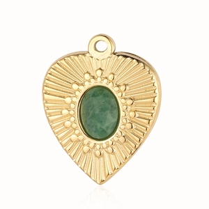 Macro view of gold heart pendant with green stone inlay and sunburst relief detail