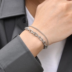 Detail of layered stainless steel chain bracelet on wrist showing metallic texture