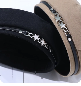Detail of beret cap featuring woolen fabric, leather strap, and silver star metal chain