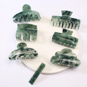 Macro shot of green marble pattern hair claws and hair clip on a white ceramic plate
