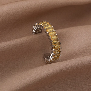 Macro shot of silver ring with yellow baguette stones on brown silk fabric background
