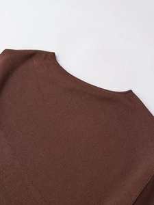 Close-up of the neckline on a dark brown knitted poncho with metallic thread texture