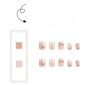 Macro detail of gradient pink press-on nails with white floral patterns and rhinestones