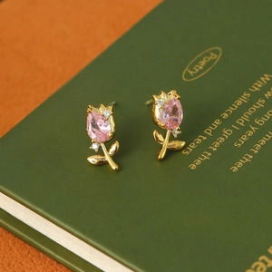 Macro detail of tulip earring with pink zircon and gold finish on a vintage book