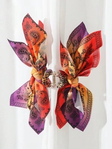 Macro shot of paisley pattern fabric bow attached to leopard print claw hair clip for women